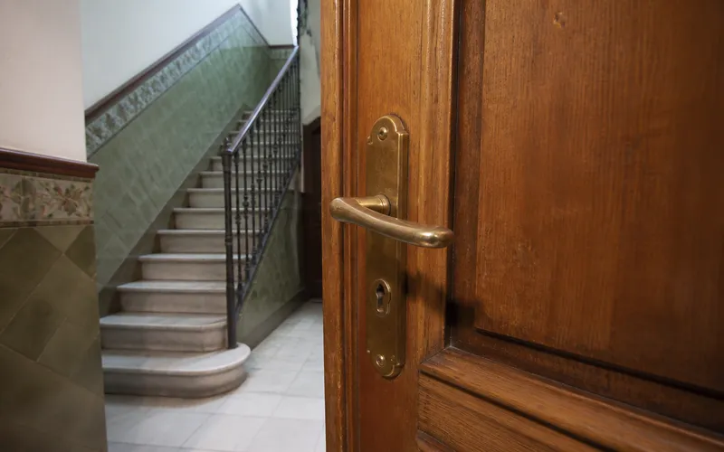 Puerta de piso entreabierta en un rellano de Barcelona, aviso típico de apertura.